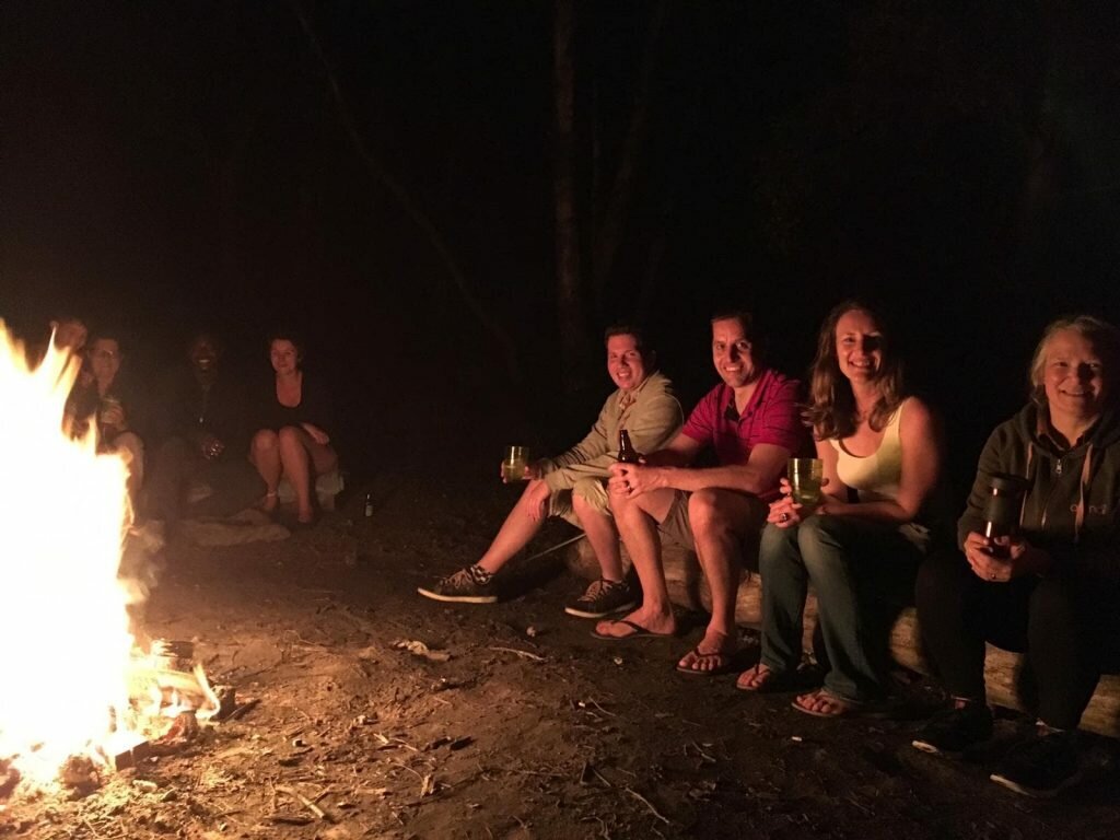 4 people sat Chilling by the camp fire at Shine camp